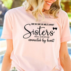 Woman wearing a pink t-shirt with a sister-themed design by a pool.