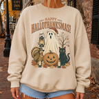 A person wearing a beige crewneck sweatshirt with a 'Happy Hallothanksgiving!' graphic featuring a ghost, turkey, jack-o'-lantern, and black cat, photographed outdoors on a brick street.
