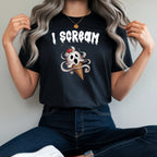 A woman wearing a black graphic t-shirt with a white 'I SCREAM' text and a skull in an ice cream cone design, paired with dark blue jeans and white sneakers, sitting on a red stool.