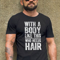 Man wearing a black t-shirt with text and sunglasses, standing against a textured wall.
