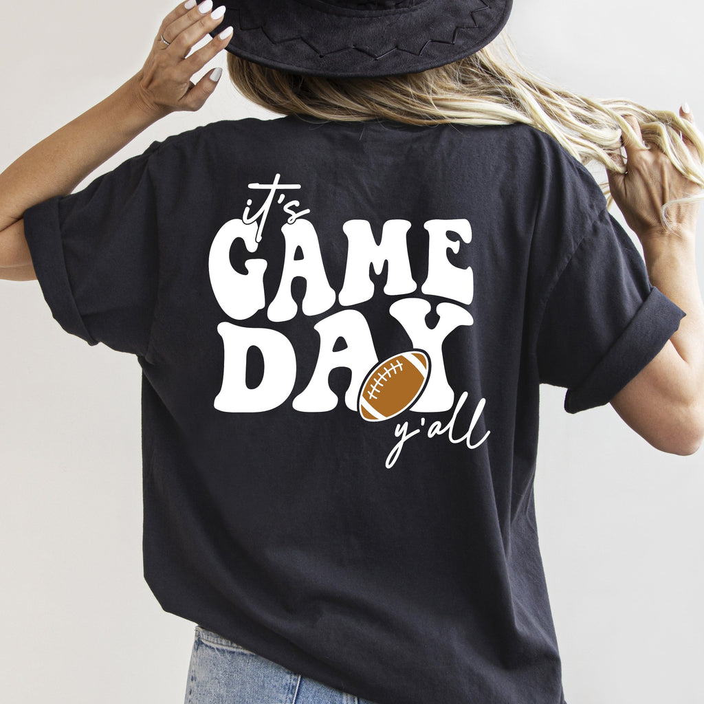 Person wearing a black t-shirt with 'It's Game Day y'all' text and football graphic.