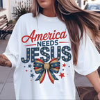 Person wearing a white t-shirt with 'America Needs Jesus' design outdoors.