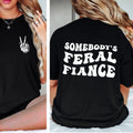 Black t-shirt with a hand gesture on the front and 'SOMEBODY'S FERAL FIANCE' text on the back.