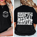 Black t-shirt with 'Bomb Ass Medical Assistant' text and smiley face design on a person.