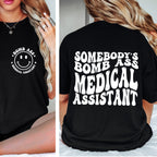 Black t-shirt with 'Bomb Ass Medical Assistant' text and smiley face design on a person.