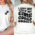 White t-shirt with paw print design on front and text on back, worn by a person.