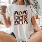 A woman sitting cross-legged on a kitchen counter wearing a white graphic t-shirt with a 3x3 grid of cute cartoon ghosts in Halloween-themed frames. She is holding a glass jar of iced coffee in a bright, modern kitchen.