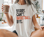 A woman sitting cross-legged on a kitchen counter wearing a white graphic t-shirt with the text 'SORRY. CAN'T.