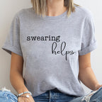 Person wearing a gray t-shirt with 'swearing helps' text.