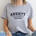 Person wearing a gray t-shirt with 'ANXIETY UNIVERSITY HONORS PROGRAM' text.