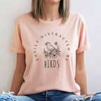 Person wearing a pink t-shirt with a bird graphic and text.