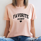 Person wearing a pink t-shirt with 'FAVORITE AUNT' text and a heart symbol on a light background