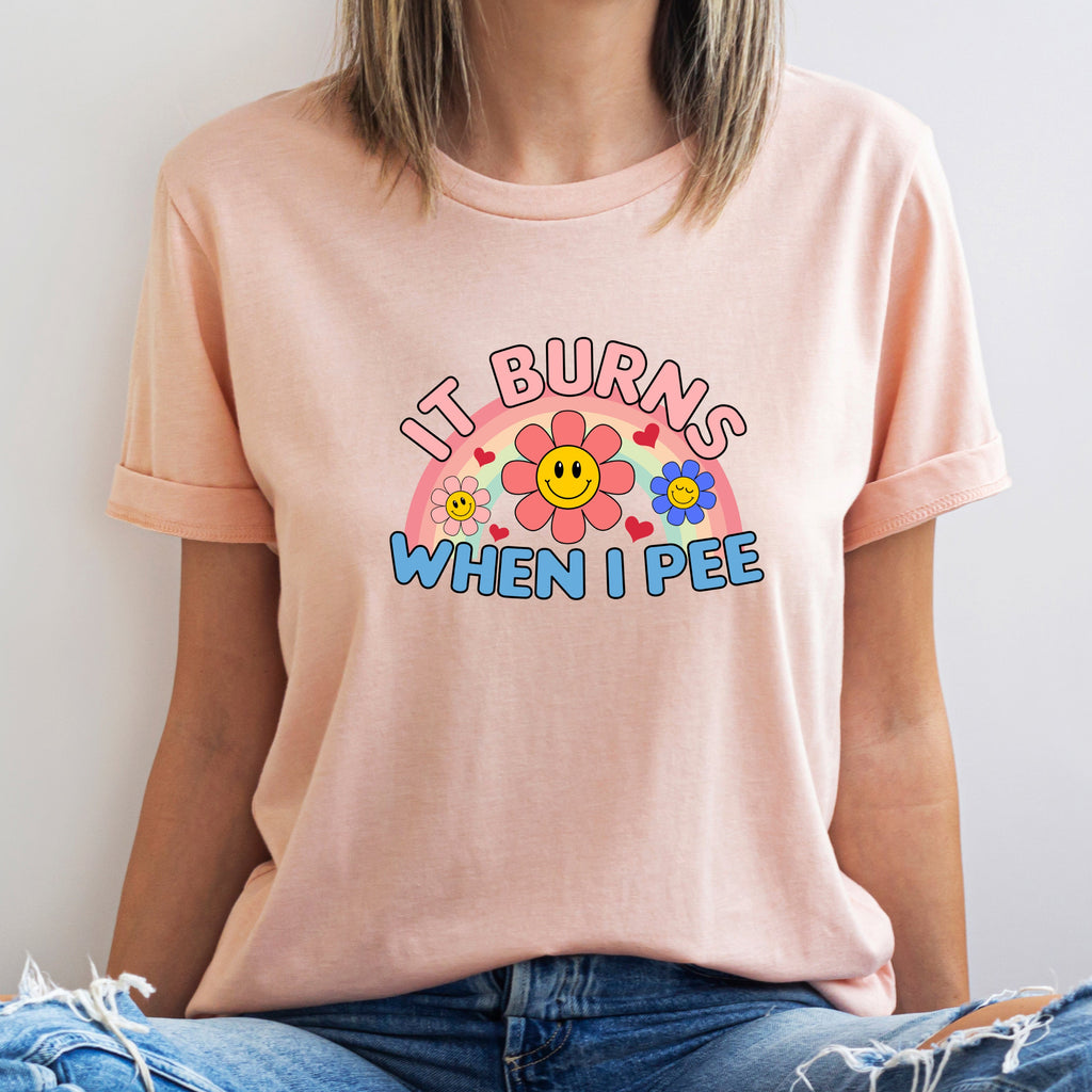 Person wearing a light pink t-shirt with colorful graphic and text against a plain background