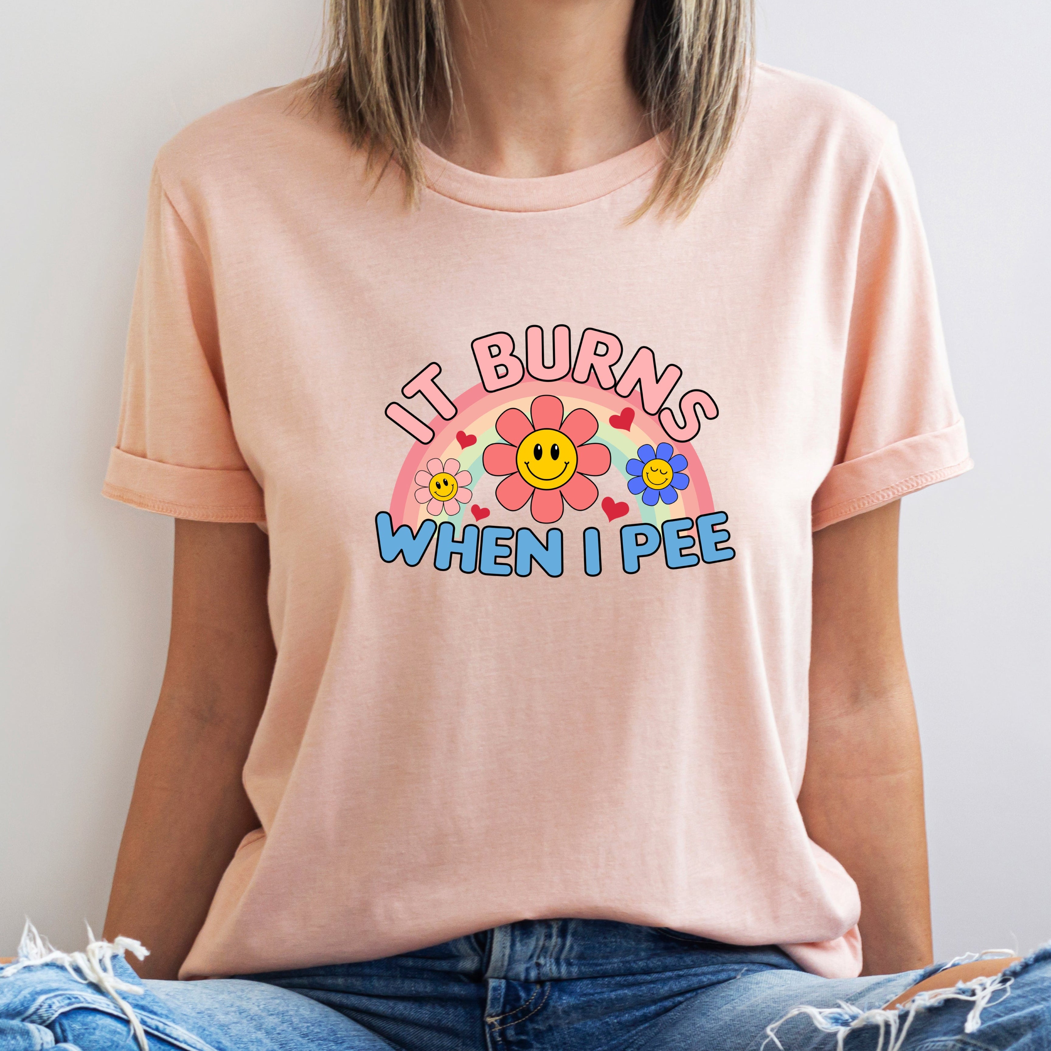 Person wearing a light pink t-shirt with colorful graphic and text against a plain background