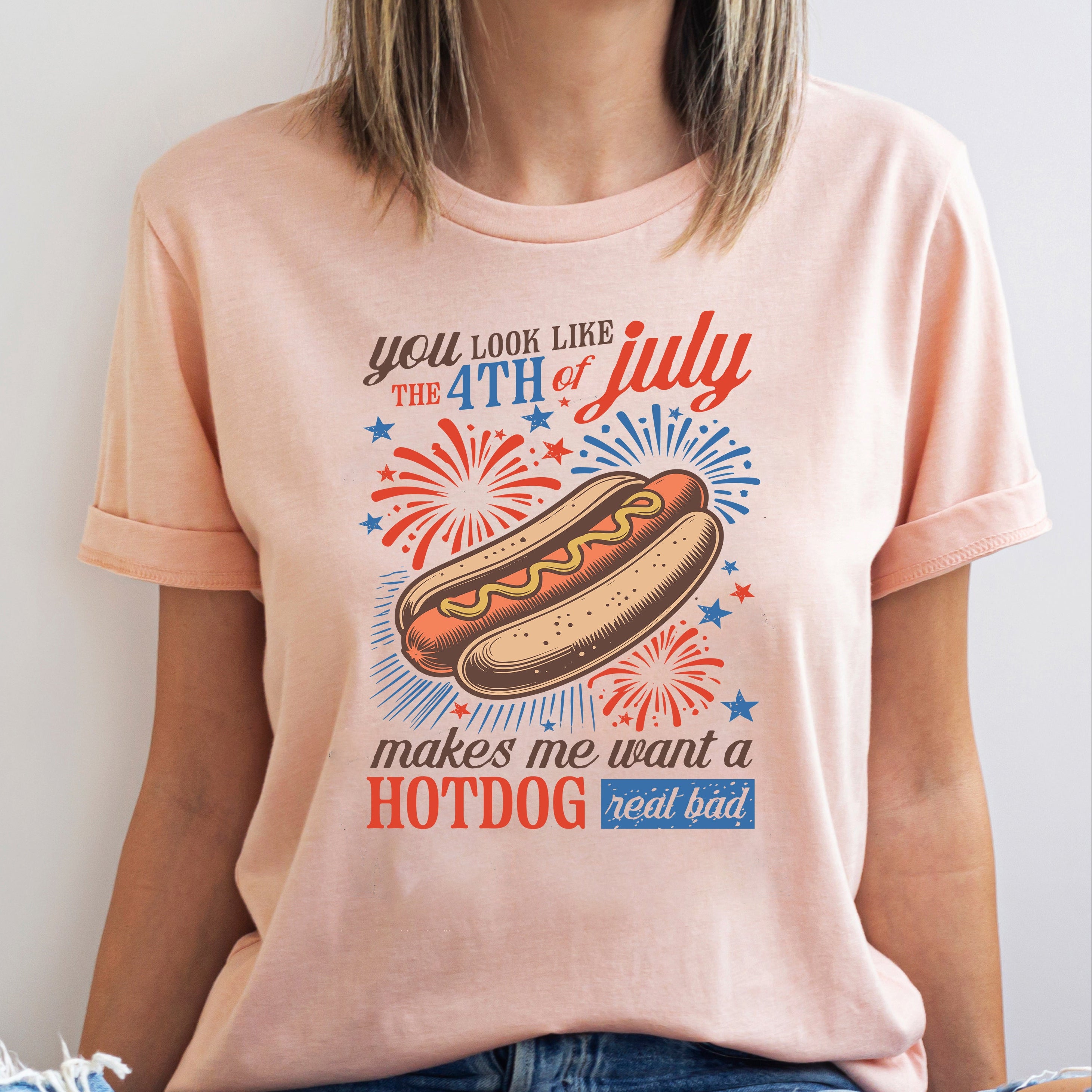 Person wearing a peach t-shirt with a hotdog graphic and text on a white background