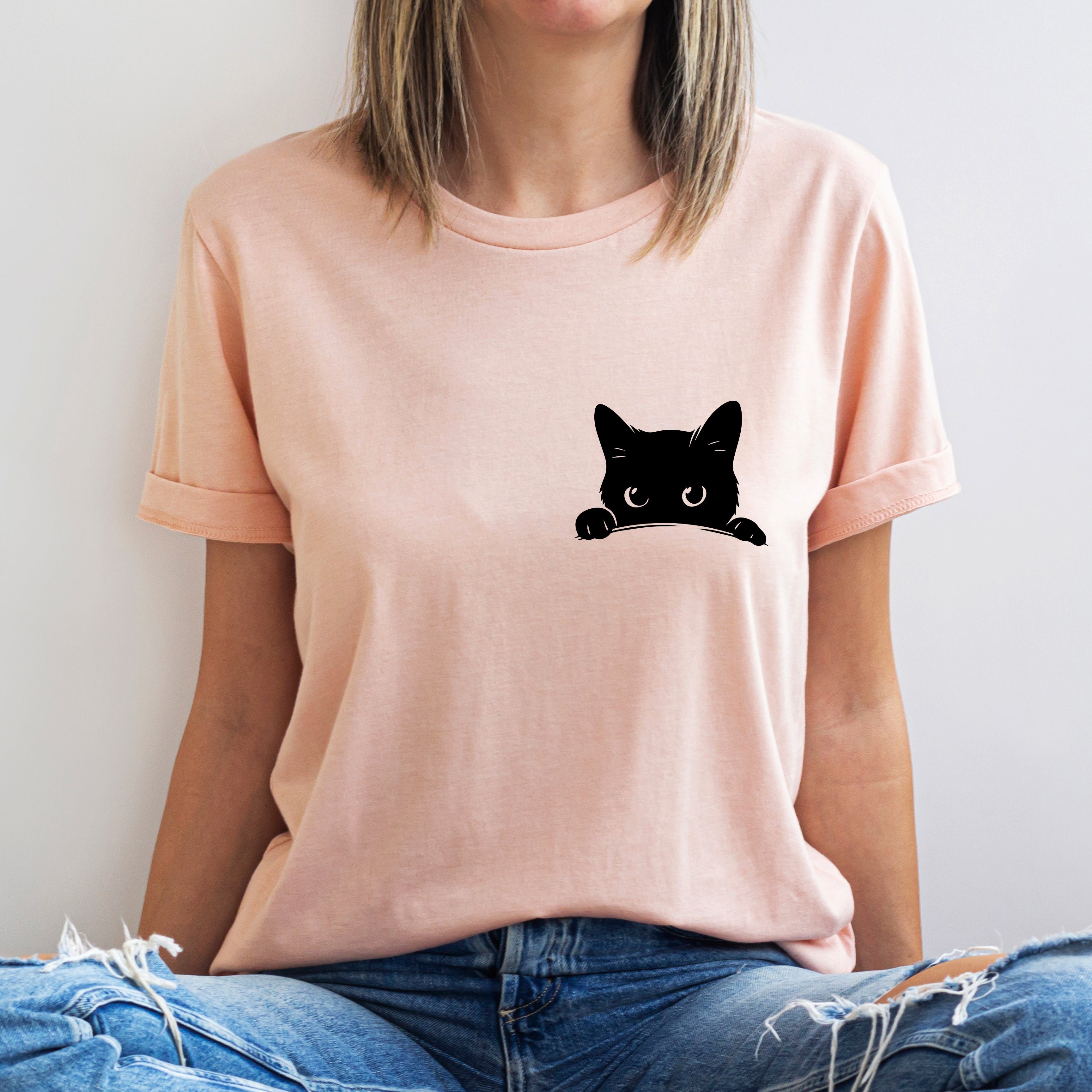Person wearing a pink t-shirt with a black cat graphic on a white background