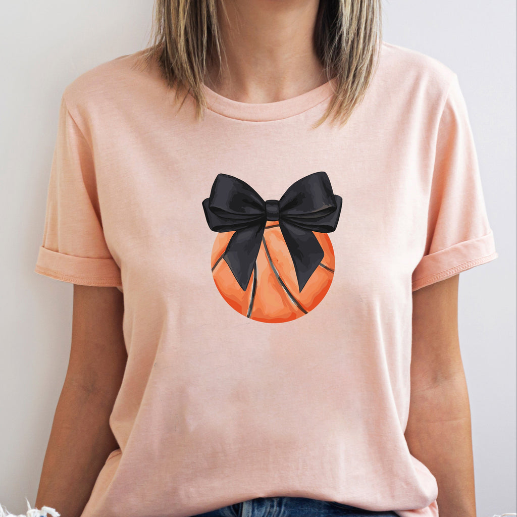 Person wearing a peach t-shirt with a black bow on an orange circle design.