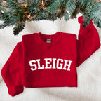 Red sweatshirt with 'SLEIGH' text under a decorated Christmas tree