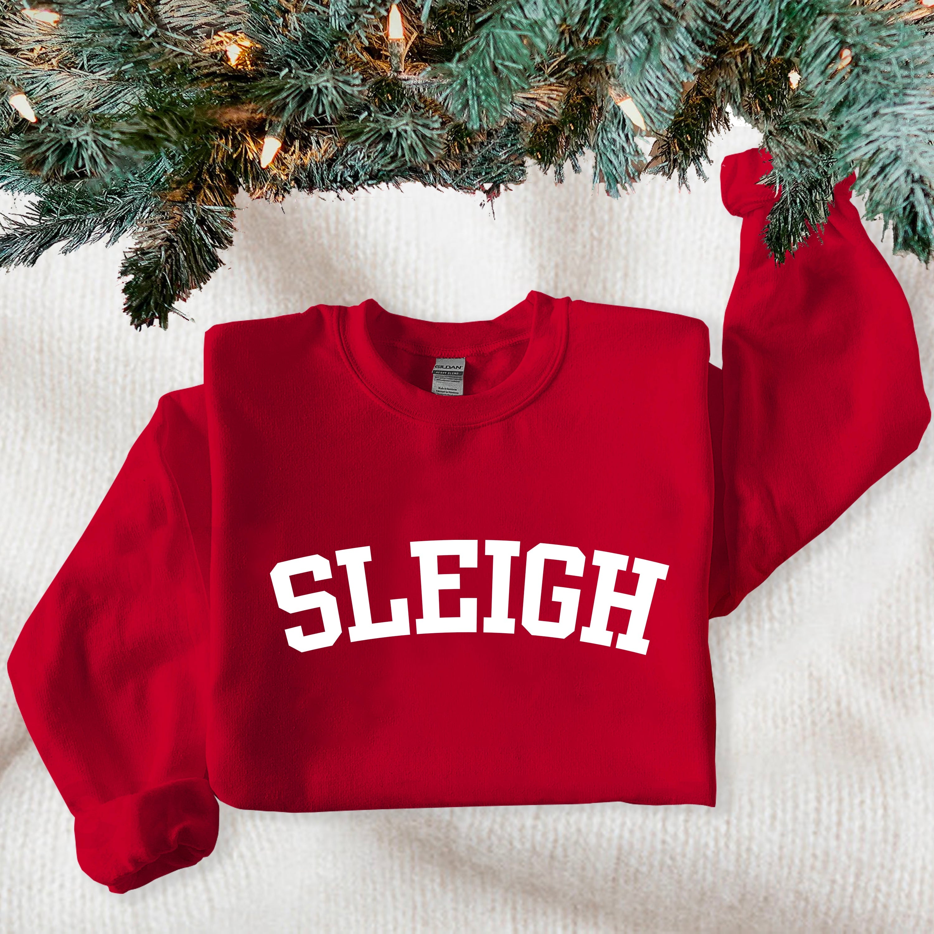 Red sweatshirt with 'SLEIGH' text under a decorated Christmas tree