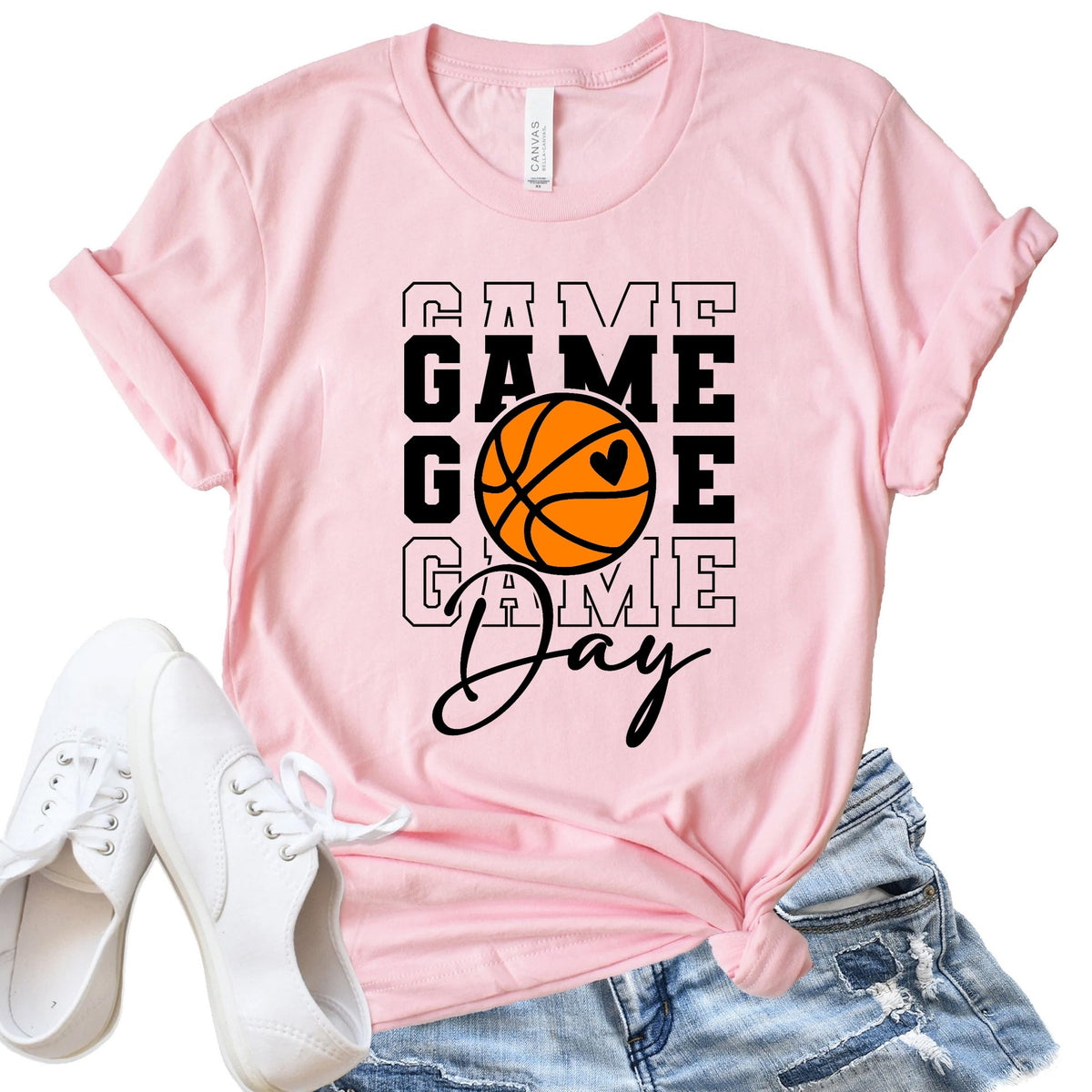 Pink t-shirt with 'Game Day' and basketball graphic, paired with white sneakers and denim shorts on a white background.