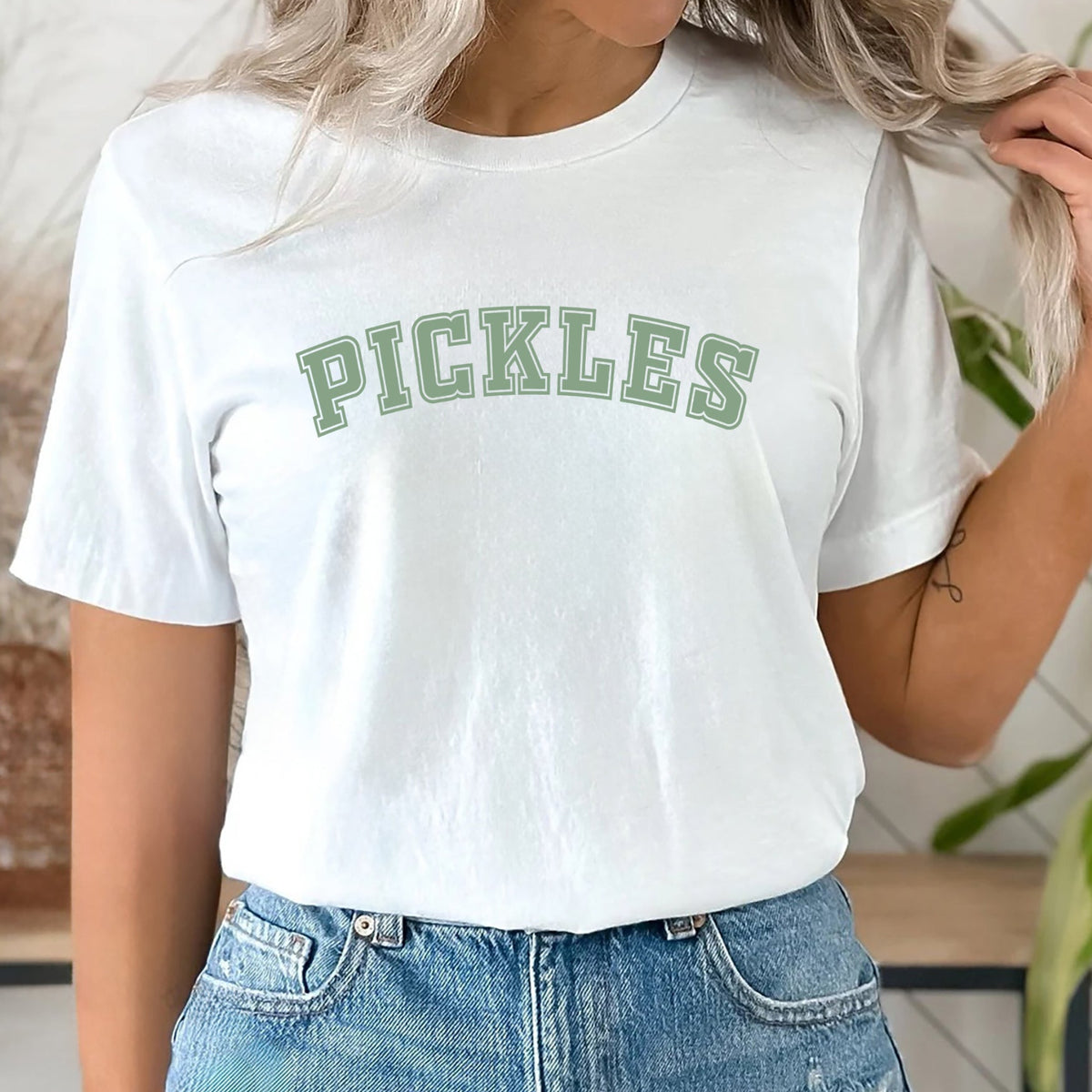 Person wearing a white t-shirt with 'PICKLES' text in a casual setting